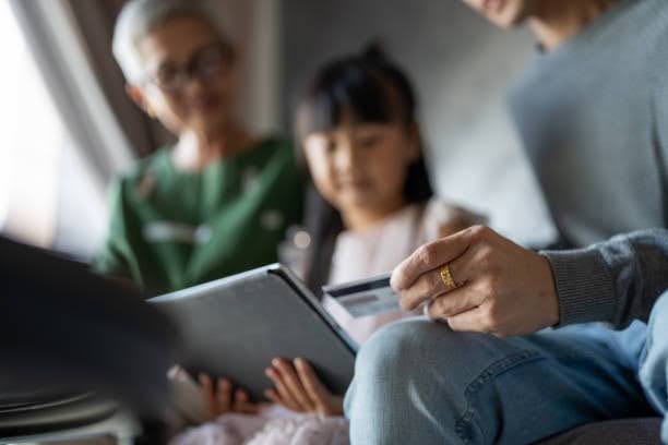 Asian family using a tablet to learn about money management and financial literacy together.
